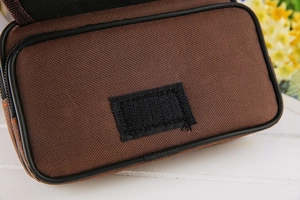 Dettaglio del borsello per cellulare in tela marrone con chiusura a strappo e cucitura arancione
