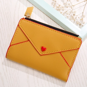 Detailed close-up of yellow PU leather heart coin purse with red edges on wood