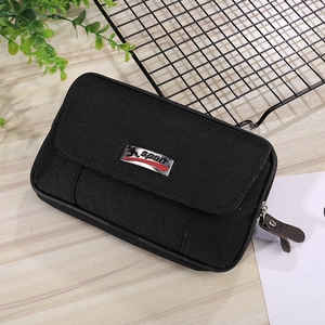 Detail view of black canvas sports waist bag with secure buckle and metal logo on wood table