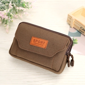 Brown canvas multi-functional waist bag with double zippers and sport label on wood desk