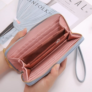 Detail of light blue leather long wallet showing pink interior card slots and wrist strap