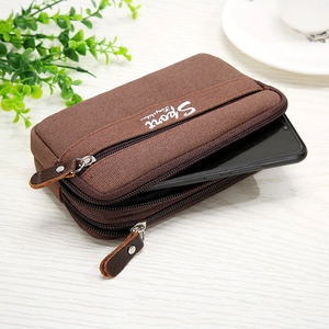Detail view of brown oxford cloth pouch with three zippers showing an internal phone pocket