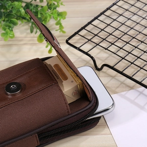 Detail view of brown canvas belt pouch with dual zippers and magnetic flap closure
