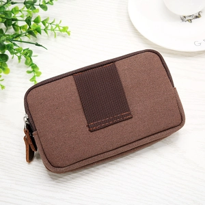 Close-up of brown Oxford canvas phone pouch with durable metal zippers on a wooden table