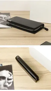 Detail of black leather long wallet featuring metal zipper and brand logo on wooden desk