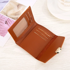 Brown snakeskin heart tri-fold wallet with card slots and metal buckle on wooden desk