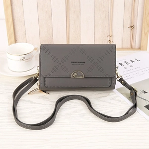 Detail of grey crossbody phone bag with laser-cut diamond pattern and gold hardware