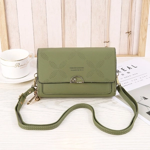 Close-up of green leather crossbody bag with diamond perforated pattern and gold hardware