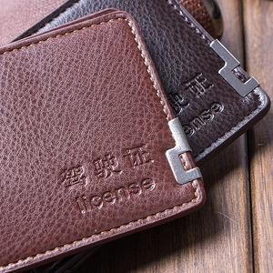 Détail macro du porte-permis en cuir avec texte embossé et coins métalliques