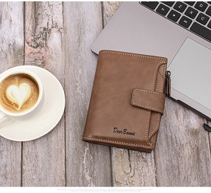 Detail of a brown leather wallet with zipper and snap button on a wooden office desk