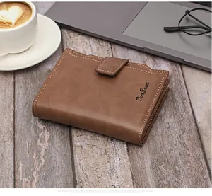 Detailed side view of a brown minimalist leather wallet with buckle on a wooden desk