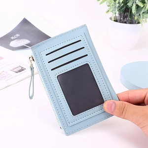 Slim light blue card holder with ID window and gold zipper detail held in hand