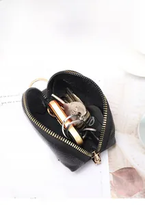 Detail of black pebbled leather coin purse with gold zipper holding car keys and coins