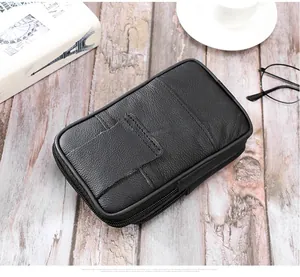 Détail d'une pochette ceinture en cuir noir avec plusieurs zips sur un bureau en bois