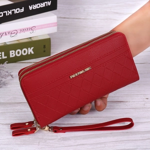Detail of red quilted leather wristlet wallet with double zippers and metal logo
