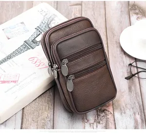 Détail d'une sacoche de ceinture en cuir marron avec trois poches zippées et texture grainée