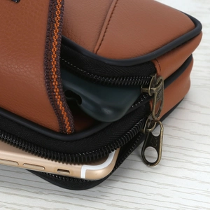 Detailed view of brown lychee grain leather phone holster with double zipper storage slots