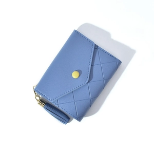 Detail of blue quilted wallet with yellow snap closure and decorative long tassel pendant