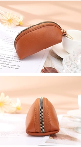 Macro detail of brown lychee grain leather purse with golden zipper and ring handle