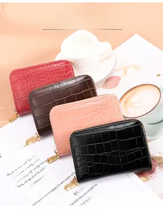 Close-up of four mini crocodile-textured zip wallets in burgundy, brown, pink, and black