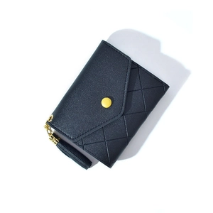 Detail view of navy blue quilted wallet with yellow button and leather tassel charm