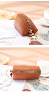 Detailed close-up of brown pebbled leather coin purse with golden zipper and ring buckle