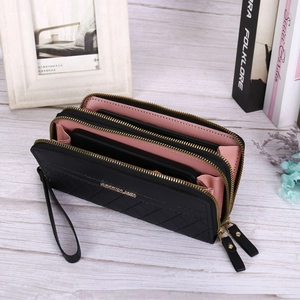 Macro detail of black quilted leather wallet showing double zippers and pink interior layers