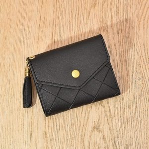 Quilted black leather wallet for women with tassel charm and gold buckle on wood surface