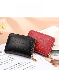 Detail of red and black crocodile textured zip wallets with gold hardware and elegant props