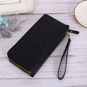 Detail of black quilted leather wallet with gold zipper and wrist strap on a white surface