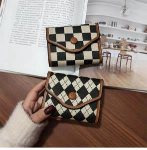 Detail of vintage checkered fold wallet with leather trim and round snap button