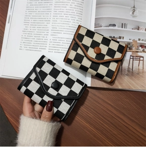 Close-up of vintage checkered print wallets in black and brown on a wooden desk