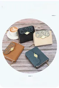 Detail of four colorful bifold wallets with leaf print and gold hardware on wood surface