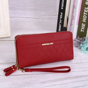 Red quilted long clutch purse with double zipper and detachable wrist strap on white wood