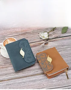 Close-up of small faux leather wallet featuring leaf prints and golden leaf metal clasp