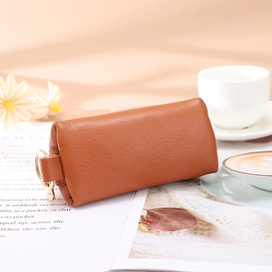 Elegant brown pebble grain leather coin purse with golden key ring on a magazine