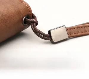 Detail of detachable wrist strap and metal hardware on brown leather wallet for men