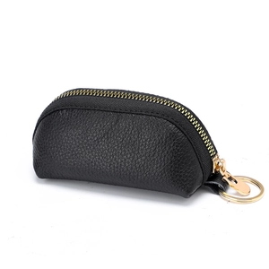 Black pebble leather coin purse with golden zipper and keychain ring on white background