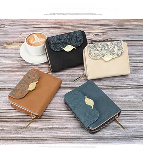 Detail of four matte leather wallets with gold leaf buckles on a grey wood table