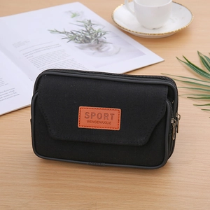 Detail of durable black canvas waist bag with flip cover and leather sport logo on table