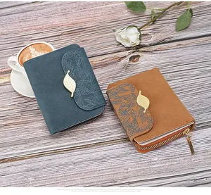 Detailed view of matte leather wallets with leaf pattern and golden leaf metal accents