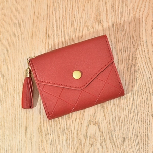 Deep red quilted leather wallet with envelope flap and tassel charm on wood background