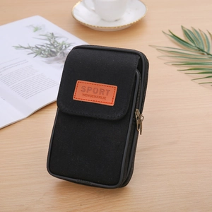 Close-up of black canvas phone belt pouch with dual zippers on a wooden table with coffee