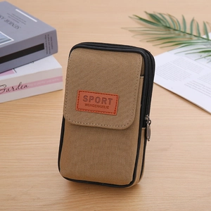 Khaki canvas belt waist bag with dual zipper compartments and flip cover on wooden desk