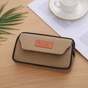 Detail of khaki canvas phone pouch with leather logo and zipper on wooden desk