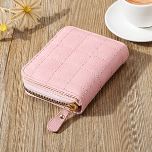 Gros plan du mini portefeuille rose matelassé avec fermeture éclair sur surface boisée