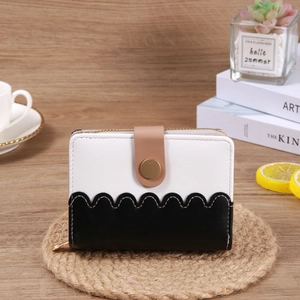 Short wave-edge wallet with contrast colors and snap closure on a woven mat