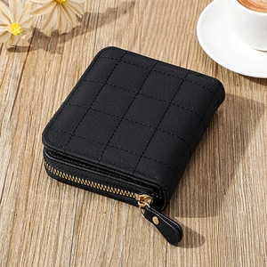 Détail du mini portefeuille matelassé noir avec fermeture éclair dorée et tirette en cuir