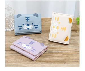 Trois mini portefeuilles tigre en bleu, blanc et violet sur une surface en bois