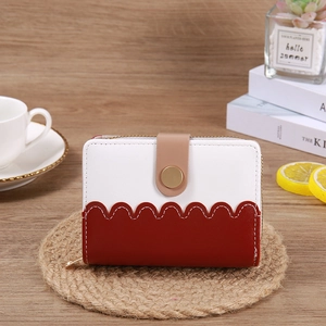 Detail view of wave-edged short wallet with gold zipper on a cozy coffee table setting
